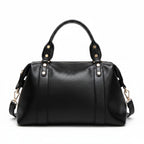 Black leather-style Boston handbag with top handles, gold hardware, and side tassel details.