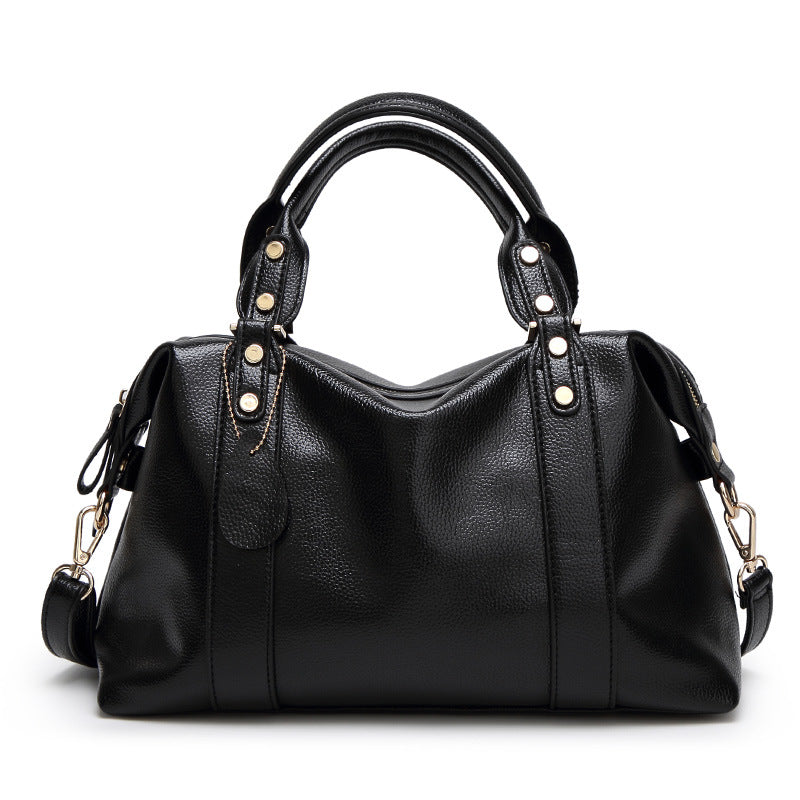 Black leather-style Boston handbag with top handles, gold hardware, and shoulder strap.