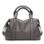 Gray leather-style Boston handbag with two handles, gold-tone hardware, and side tassel details.