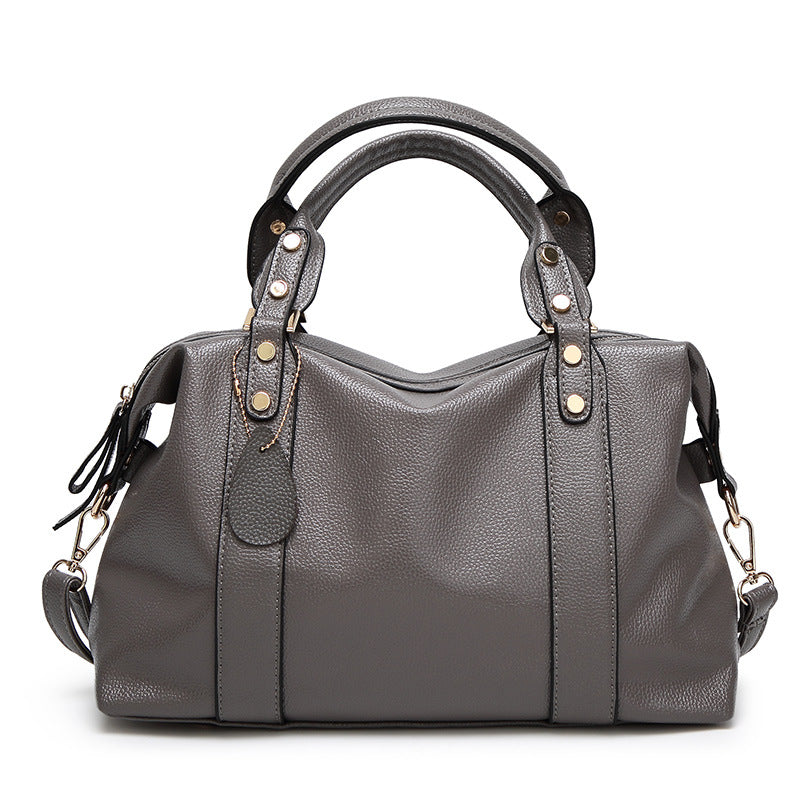 Gray leather-style Boston handbag with two handles, gold-tone hardware, and side tassel details.