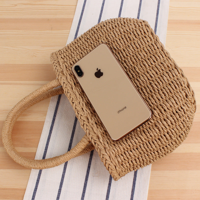 Woven khaki tote bag with long handles, phone resting on the woven surface