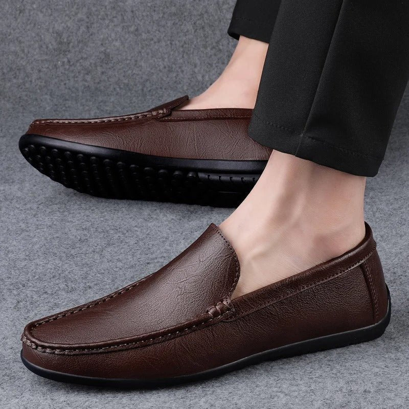 Men’s brown leather slip-on loafer worn with dark pants; textured rubber sole