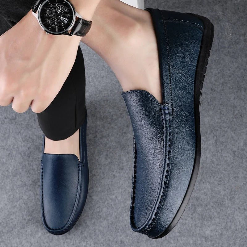 Men’s blue leather slip-on loafer pair worn with dark pants; stitched vamp detail