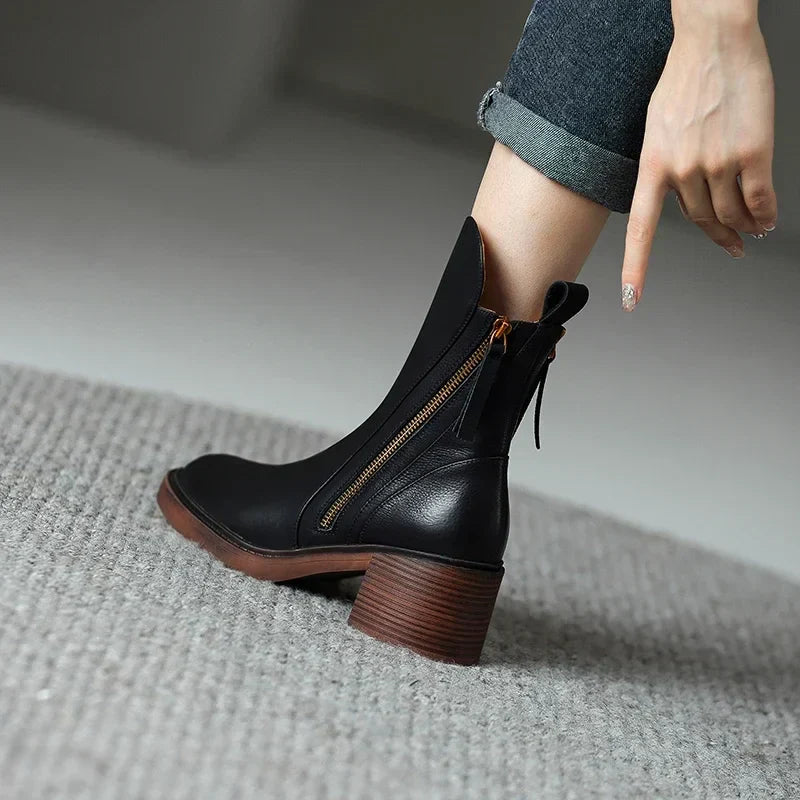 Black ankle boots with side zipper and block heel, worn with cuffed jeans