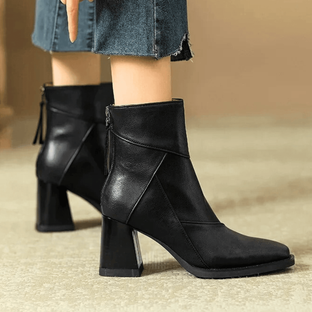 Black ankle boots with block heels and diagonal seam panels, styled with jeans