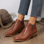 Women’s brown ankle boots with side zipper, tan sole edge, and low block heel