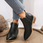 Women’s black ankle boots with side zipper and tan sole, styled with cropped jeans