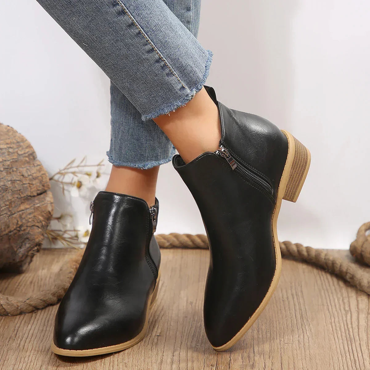 Women’s black ankle boots with side zipper and tan sole, styled with cropped jeans