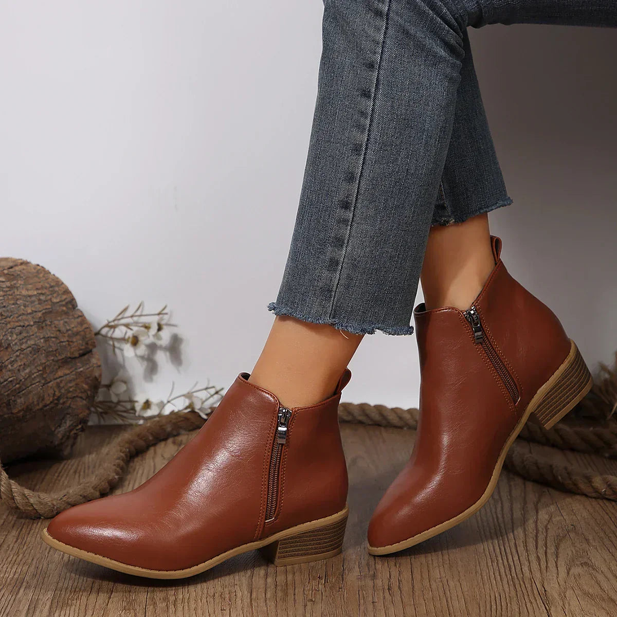 Women’s brown ankle boots with side zipper and tan sole, worn with cuffed jeans