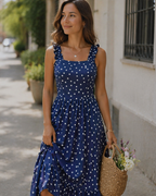 Navy blue polka-dot women's midi dress with square neck and ruffled elastic straps, tiered hem.