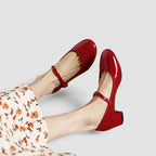 Red Mary Jane pumps with ankle strap and rounded toe, side view