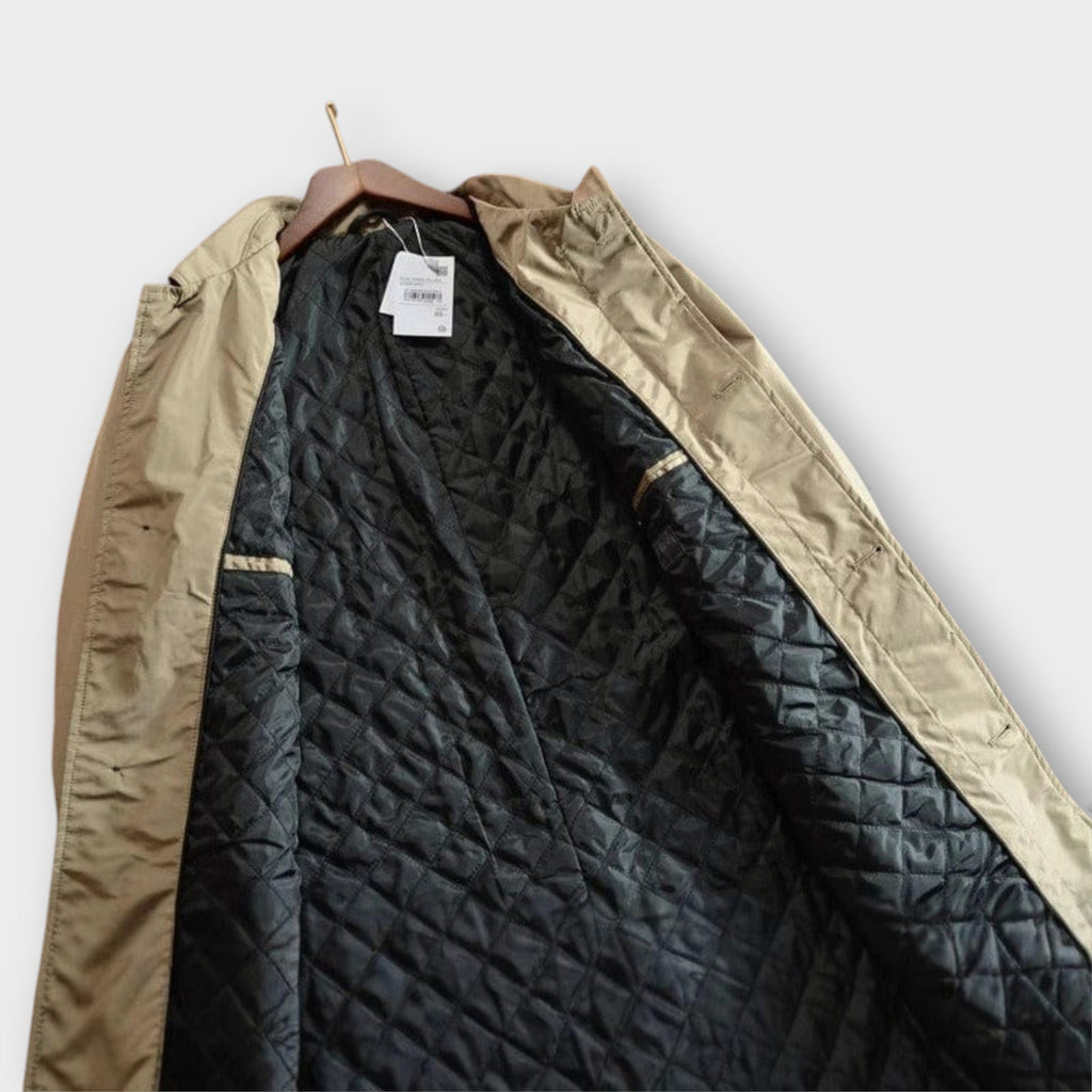 Men's beige overcoat interior lining with quilted pattern and inside label tag.