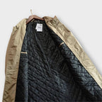 Men's beige overcoat interior lining with quilted pattern and inside label tag.