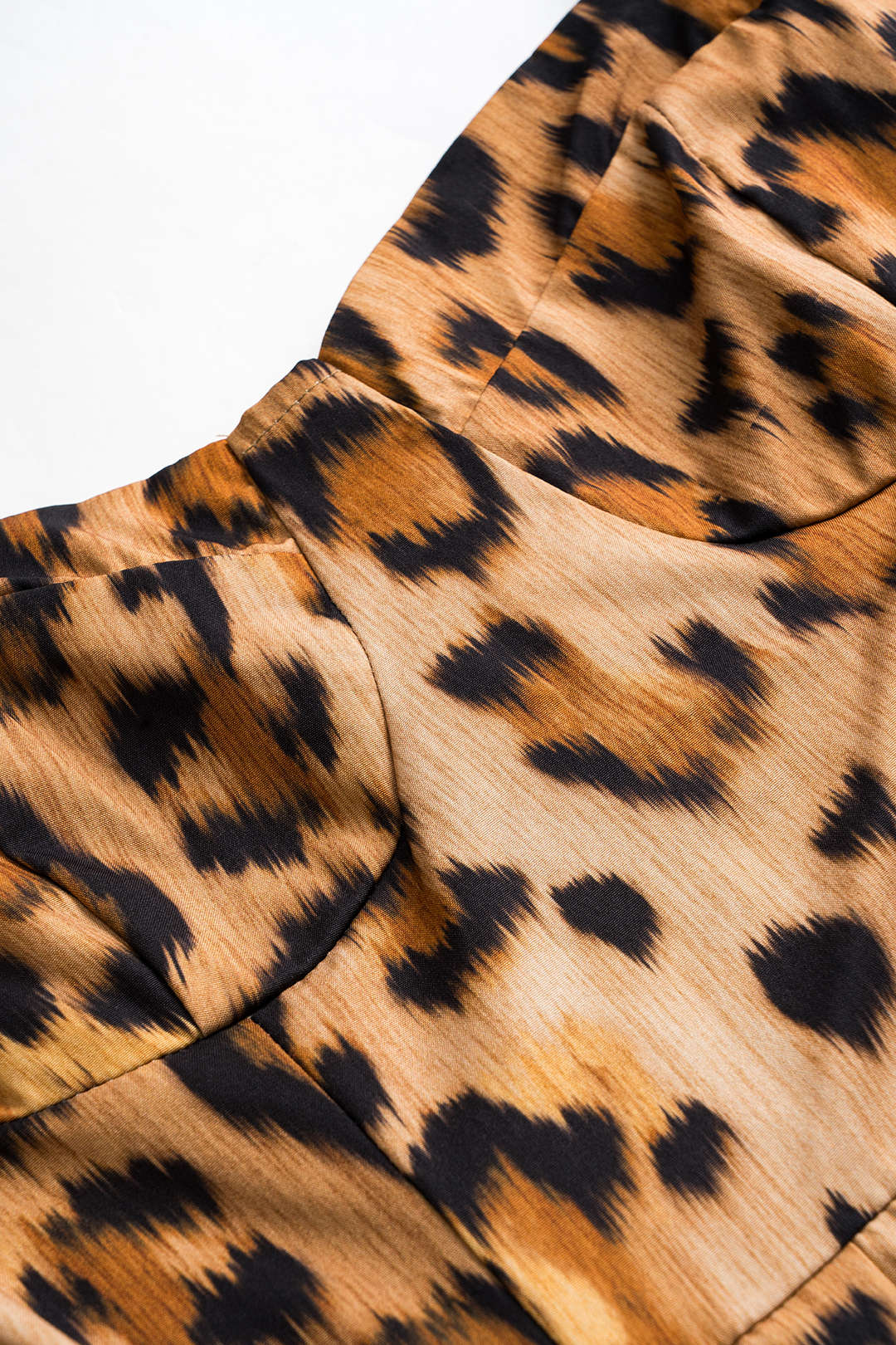 Leopard print fabric close-up with draped folds in tan and black
