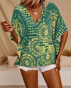 Green oversized tunic blouse with V-neck and short loose sleeves, ornate yellow patterned print