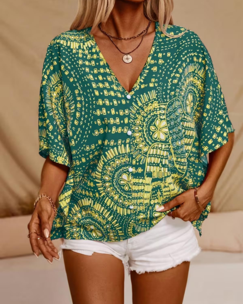 Green oversized tunic blouse with V-neck and short loose sleeves, bright yellow ornate print