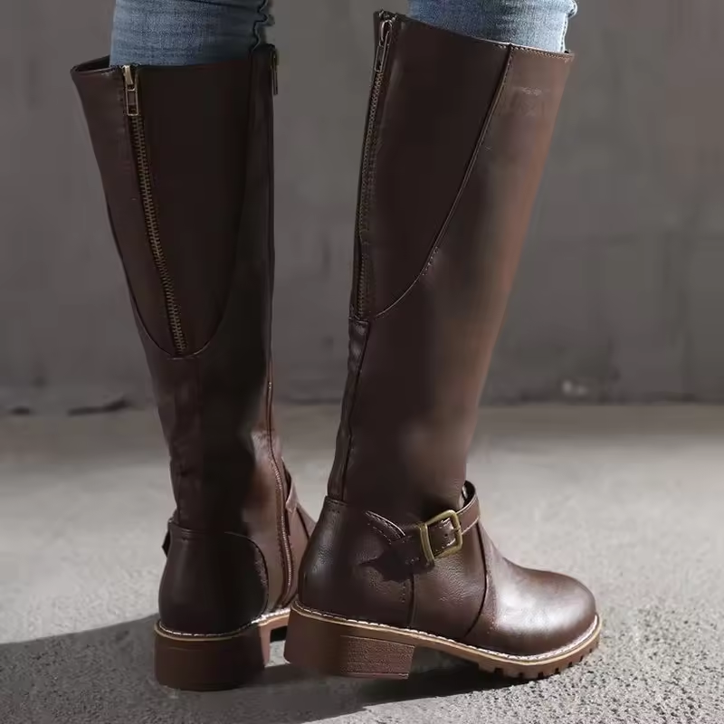 Dark brown knee-high flat-heel boots with side zipper and front buckle strap.