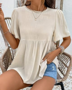 Beige short-sleeve peplum top with round neck and pearl-trim cuffs