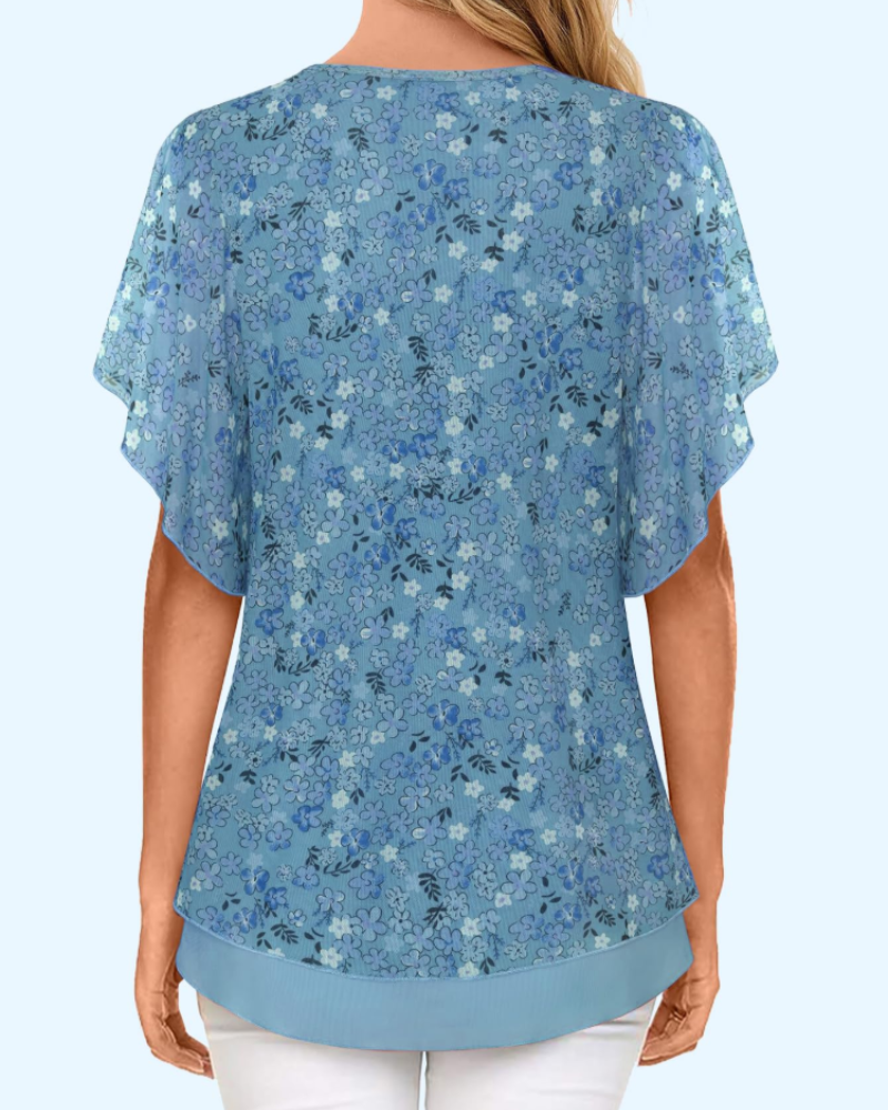 Back view: blue floral V-neck knit blouse with short ruffled sleeves and layered hem