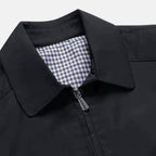 Close-up of black jacket collar with checked lining and zip front