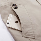 Beige hooded field coat close-up: snap button and front pocket detail.