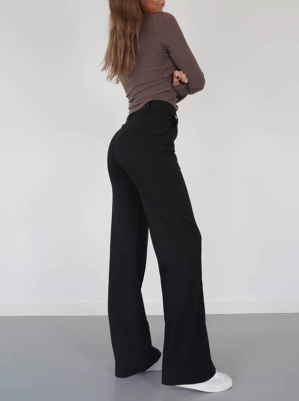 Black relaxed wide-leg trousers, side view showing wide, flowing leg opening