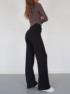 Black relaxed wide-leg trousers, side view showing wide, flowing leg opening