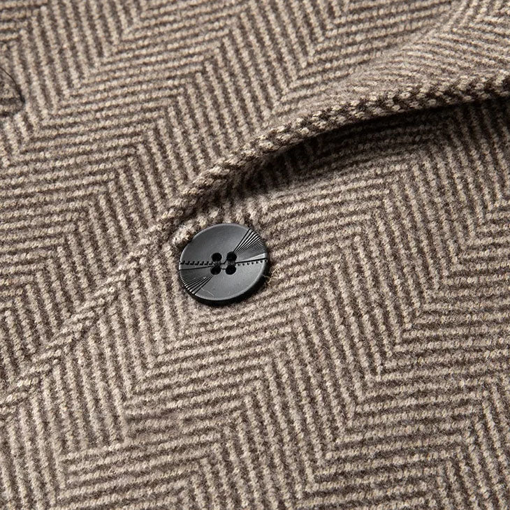 Khaki overcoat button close-up on herringbone wool texture