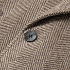 Khaki overcoat button close-up on herringbone wool texture
