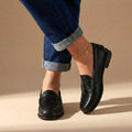 Black leather penny loafers with moccasin stitching and penny strap detail