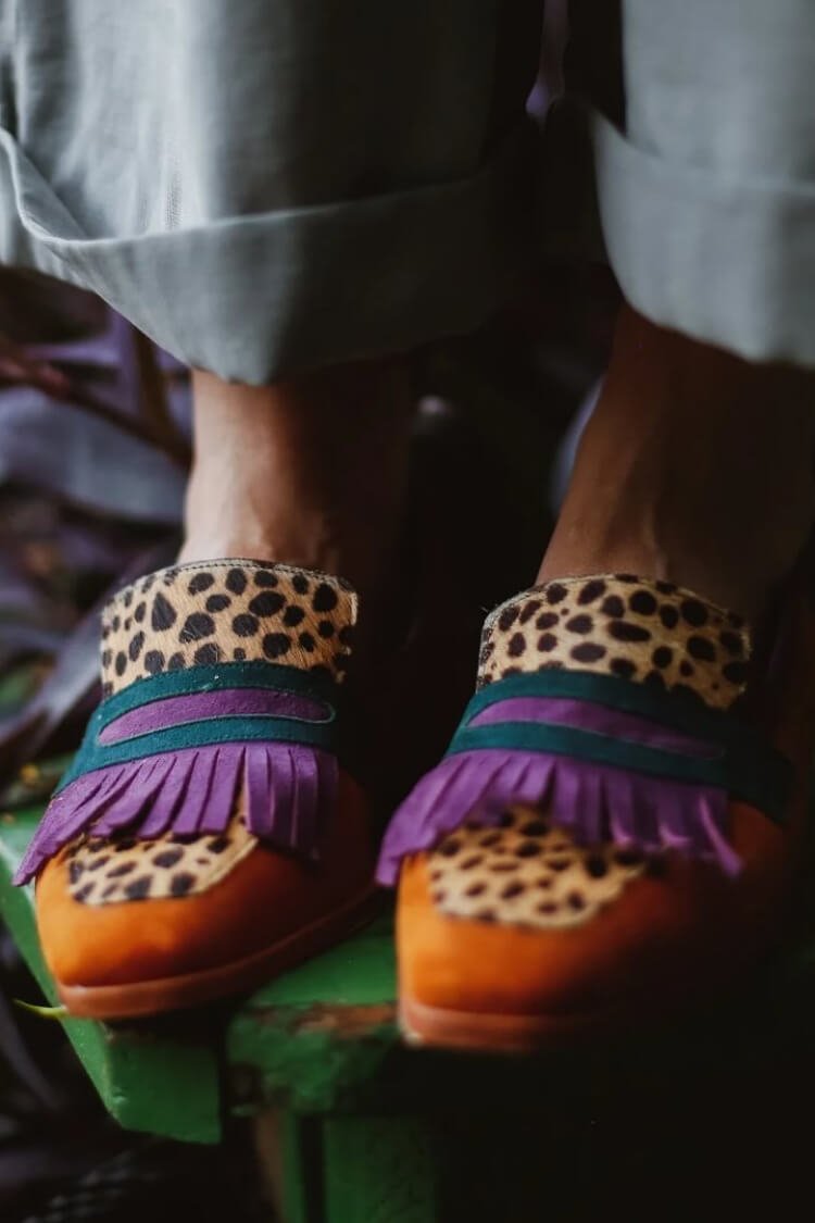 Pair of brown animal-print leather loafers with purple fringe across vamp and strap