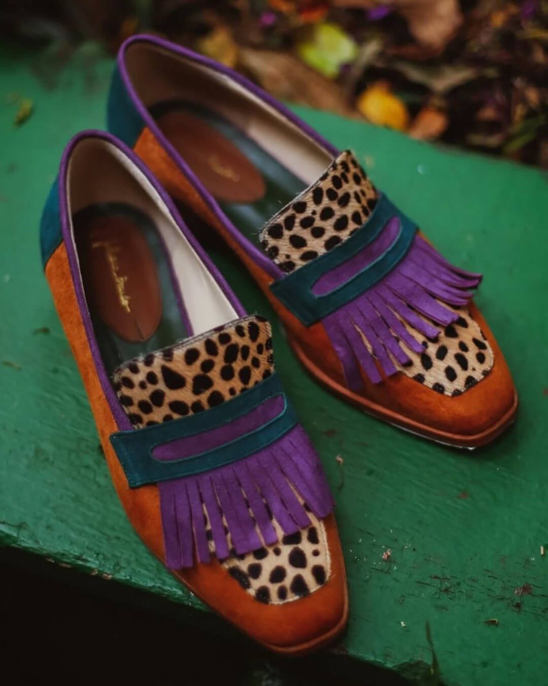 Brown animal-print leather loafers showing rounded toe, purple fringe and bar strap
