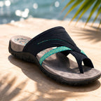 Navy thong flip-flops with teal patterned strap on a sandy surface