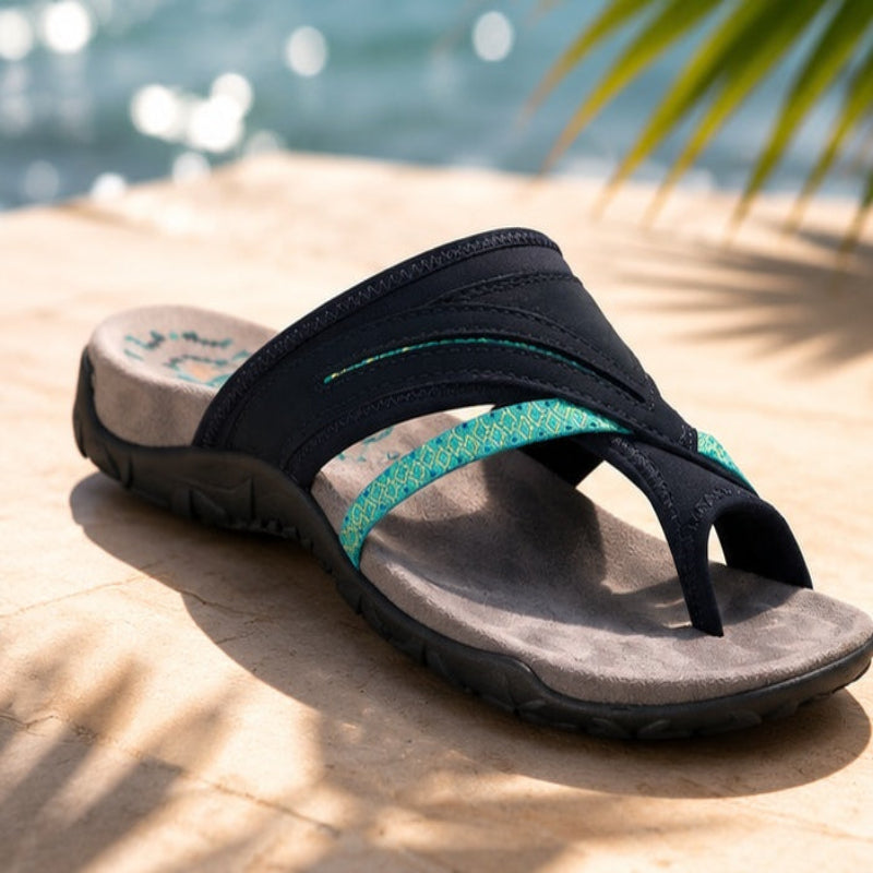 Navy thong flip-flops with teal patterned strap on a sandy surface
