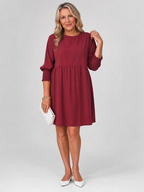 Burgundy long sleeve mini dress with smocked cuffs and gathered waist skirt