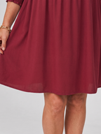 Burgundy mini dress close-up of gathered skirt and long sleeve smocked cuffs