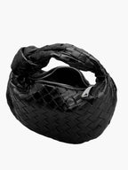 Black braided vegan leather crossbody bag with zipper opening and woven texture.