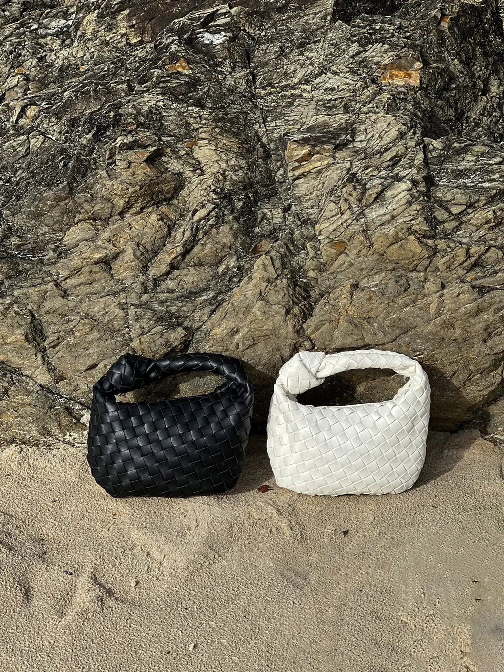 Braided vegan leather crossbody bags, one black and one white, small loop handles.