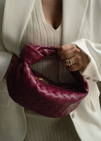 Wine red braided vegan leather crossbody bag with woven pattern and rounded handle.