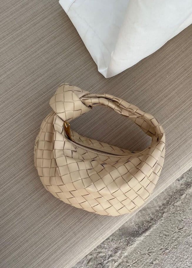 Beige braided vegan leather crossbody bag with woven pattern and rounded loop handle.