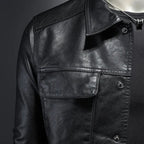 Black leather motorcycle-style jacket close-up of snap collar and chest pocket flap.