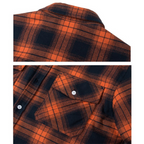 Sherpa-lined plaid shirt jacket fabric detail in orange and dark navy with buttoned flap pockets
