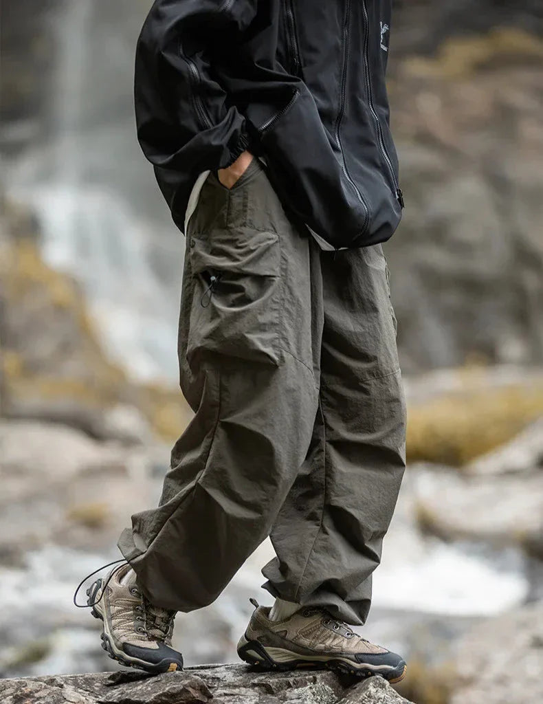 Black relaxed cargo trousers with side flap pockets and elastic cuff openings
