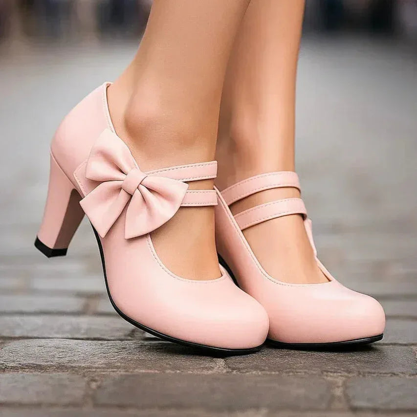 Pink bow detail heeled pumps with ankle strap and front bow detail, side view