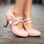 Pink bow detail heeled pumps with ankle strap and front bow detail, side view
