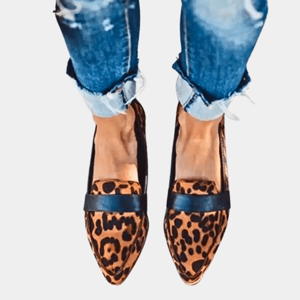 Leopard print suede slip-on loafers with buckled strap detail and tan sole.