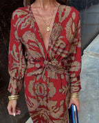 Red patterned V-neck midi dress with gathered tie waist and long sleeves with cuff trim.
