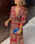Red patterned midi dress with V-neck, tie waist detail, long sleeves and gold cuff accents.