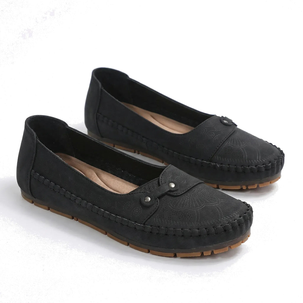 Black suede loafers with round toe, moc stitching, and hook-and-eye strap