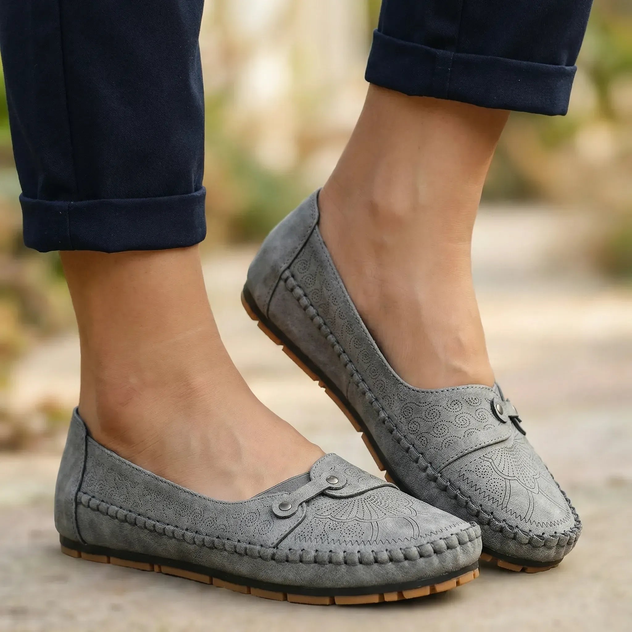 Grey suede loafers with round toe, moc stitching, and hook-and-eye strap